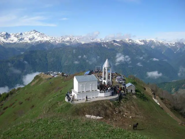 A Church in front of Georgian mountains with snowy peaks