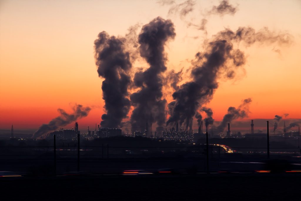 smoking chimneys in an industrial area in front of a sunset