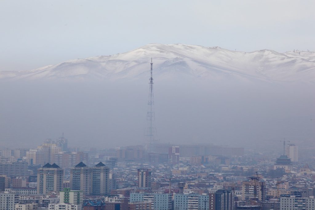 Smog over a city in Mongolia with mountains in the background.