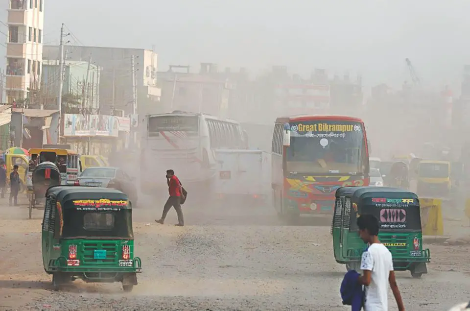 A busy street in Bangladesh. Humans and busses on a dusty road.